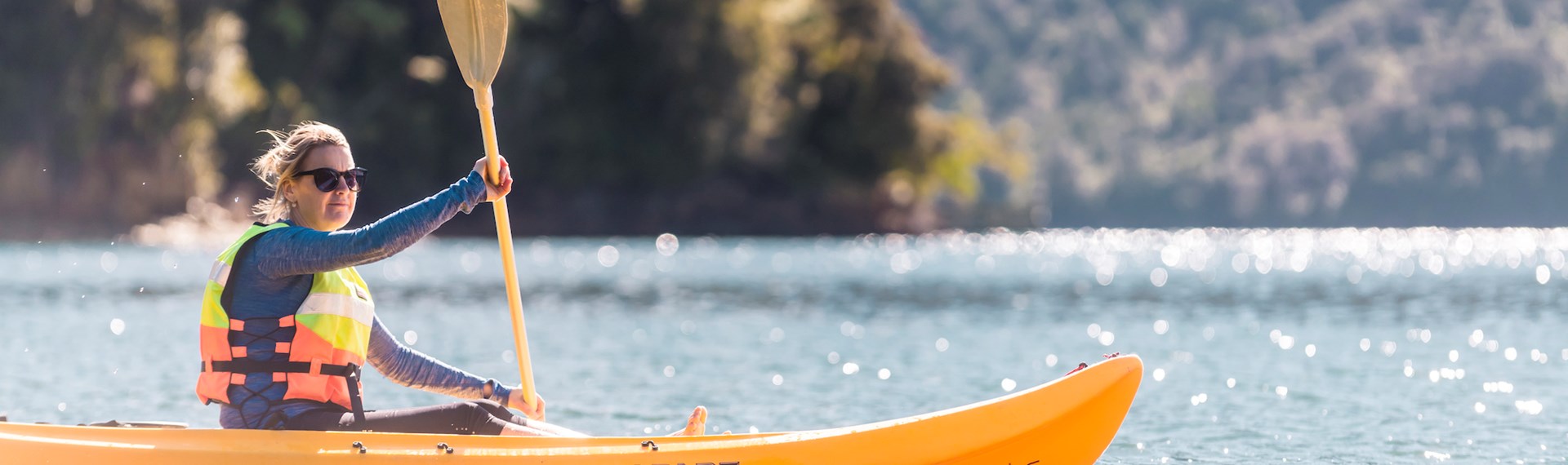 A women admires the view while kayaking around Punga Cove in the Marlborough Sounds in New Zealand's top of the South Island