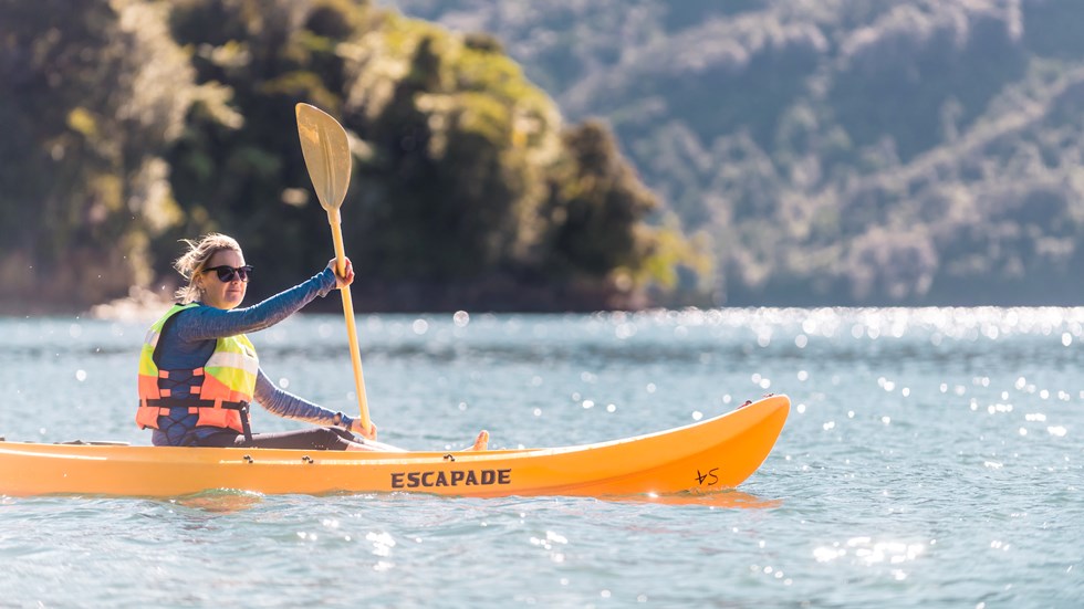 A women admires the view while kayaking around Punga Cove in the Marlborough Sounds in New Zealand's top of the South Island