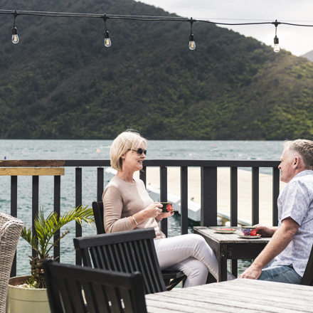A couple enjoy their coffee at Punga Cove - accompained by views of Endeavour Inlet from the Boatshed Cafe and Bar in New Zealand's South Island Marlborough Sounds