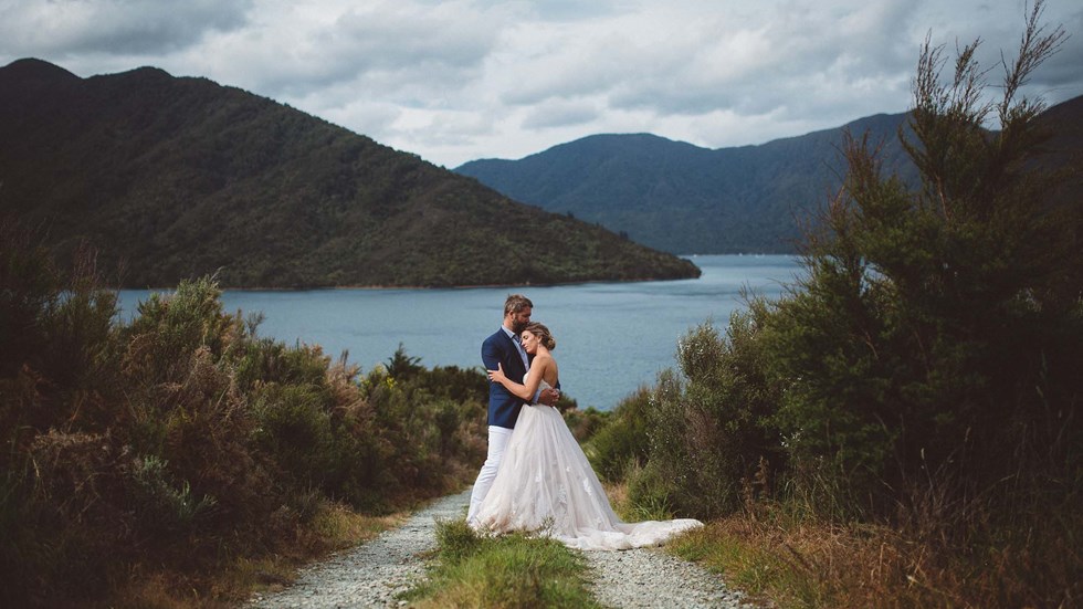 Endeavour Inlet provides a picturesque background for this bride and groom's hug at Punga Cove in New Zealand's South Island Marlborough Sounds